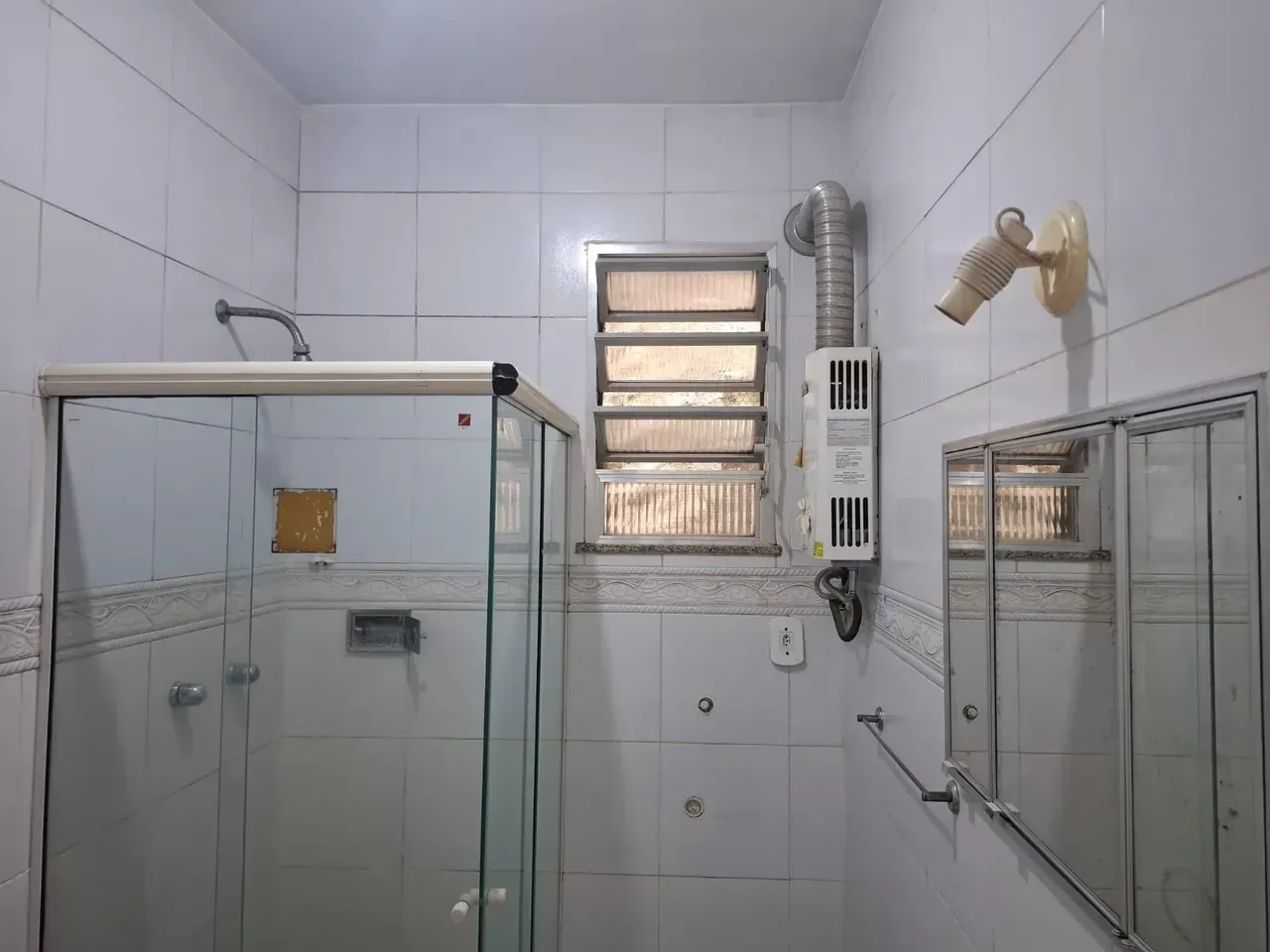 Banheiro com box de vidro e ducha elétrica em studio